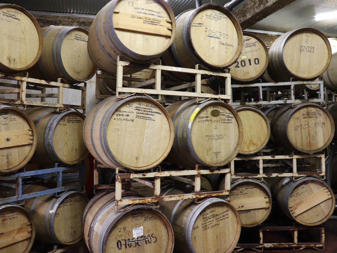 barrels stacked on racks with beer names sharpied onto them